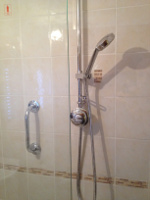 a chrome shower head and chrome handle on the shower cubicle wall