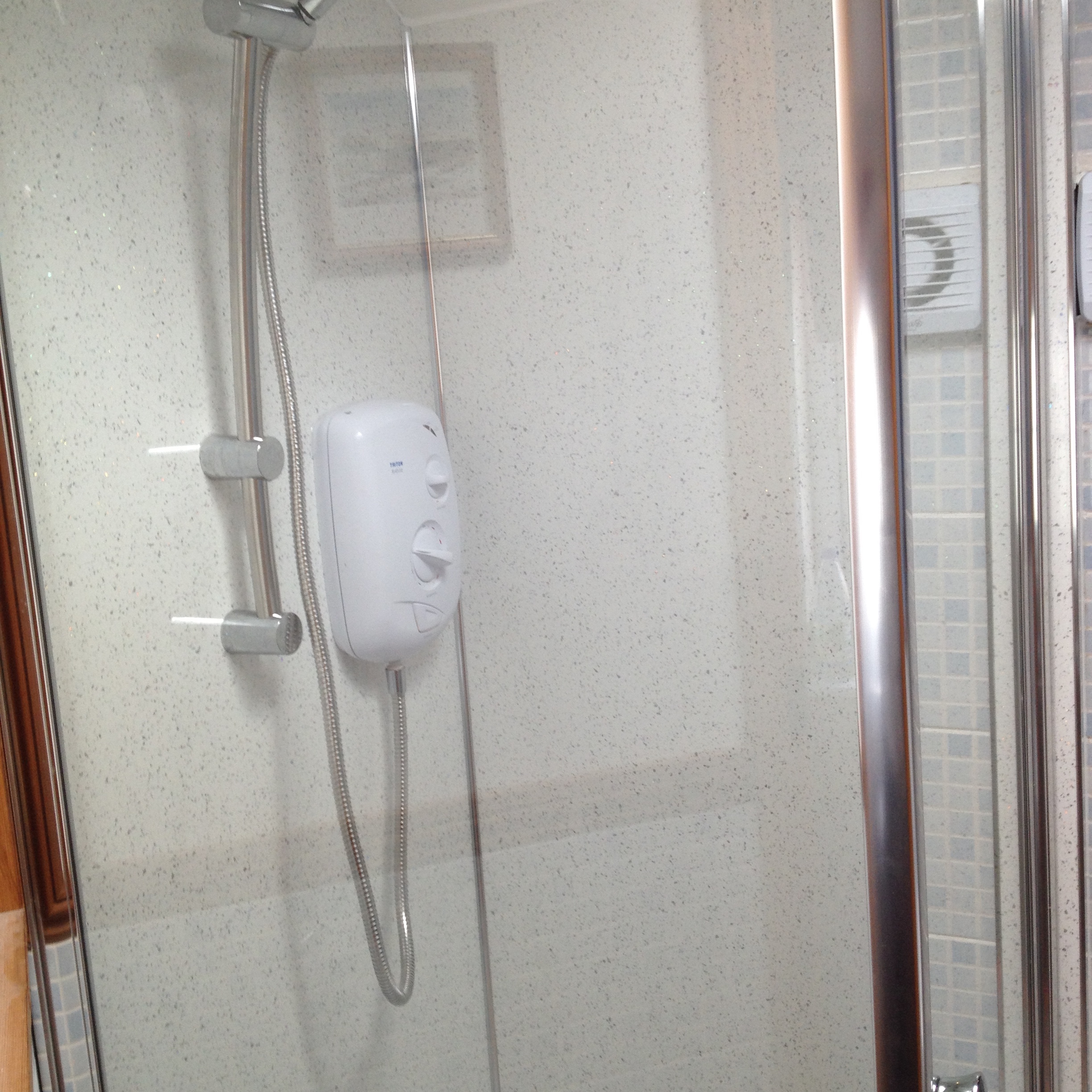 white electric shower in shower cubicle